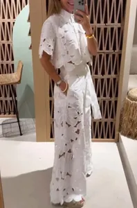 Stylish white floral laser-cut two-piece set featuring short sleeve shirt and wide-leg pants.