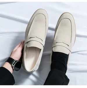 Top-down detail of men's beige suede loafers showing stitching and premium texture.