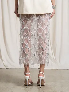 Détail d'une jupe midi blanche à sequins et franges à taille haute avec motif diamant élégant
