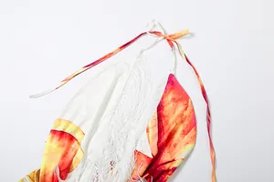 Detailaufnahme eines Kleides mit abstraktem Druck, Neckholder und weißen Fransen.