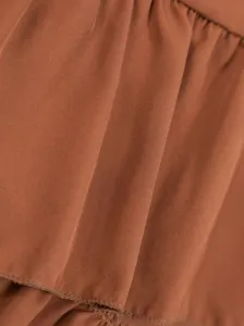 Primer plano detallado de la textura de la tela y el dobladillo con volantes de falda marrón.