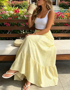 Donna che indossa una gonna lunga a righe gialle a vita alta in un giardino tropicale.