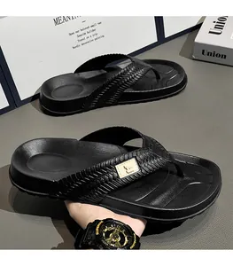 Close-up detail of black men's flip-flops with woven texture straps and thick soles