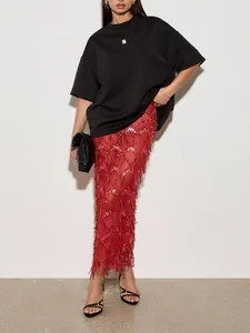 Détail élégant d'une jupe longue à paillettes rouges avec des accents de franges.