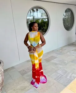 Full view of a model in a colorful sleeveless tie-dye maxi dress with twist waist detail
