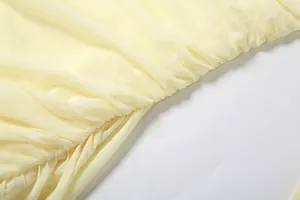 Gros plan détaillant la texture du tissu en maille plissée jaune clair pour ensemble femme