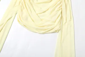 Vue détaillée de la texture froncée d'un haut en mesh jaune pâle à manches longues