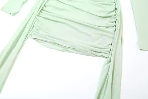 Détail d'une robe en maille froncée vert clair avec manches à passe-pouce et rubans
