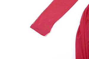Détail de la manche en mesh avec trou pour le doigt sur la robe plissée rouge.