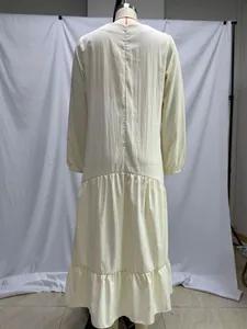 Vista posterior de un vestido maxi holgado de manga larga en color crema con volantes.