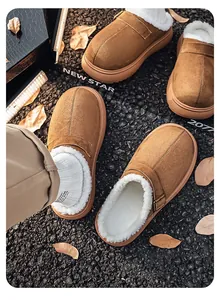 Detail of brown suede clogs with white fleece lining on a gravel path with leaves.