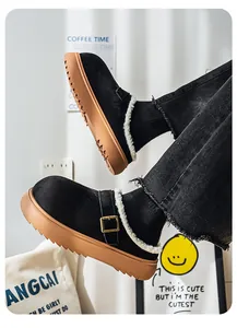 Detail of thick-soled black suede clogs with warm white fur lining and metal buckle