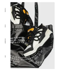 Close-up van zwart-witte chunky sneakers met dikke veters in een zwarte glanzende tas