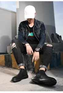 Stijlvolle zwarte Chelsea boots voor heren in een urban outfit met gescheurde jeans.