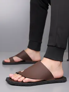 Vue de côté détaillée des tongs pour hommes en cuir marron avec un pantalon noir