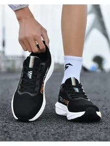 Dettaglio di scarpe da corsa in mesh nero con spesse suole bianche su un percorso in asfalto