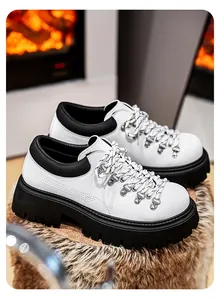 Close-up van witte herenplatform schoenen met dikke zwarte profielzolen en metalen haken.