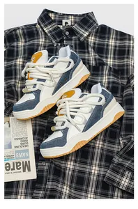 Close-up van retro denim en witte chunky sneakers met dikke touwveters op geruit shirt.