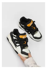 Zijaanzicht van retro dikke bread sneakers met dikke zwarte veters en oranje accenten