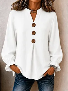 Detail of white V-neck long sleeve blouse featuring large buttons and ruffled cuffs.