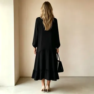 Vista trasera de un vestido largo negro de manga larga con dobladillo de volantes en capas.
