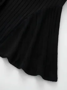 Macro view showing the texture of black ribbed fabric on an A-line skirt hemline.