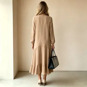 Vista trasera de un vestido largo beige de manga larga con detalle de bajo con volantes.
