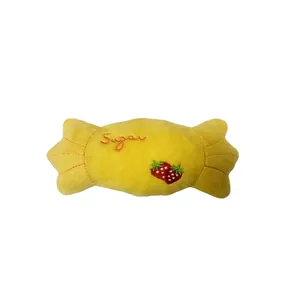 Détail d'un jouet en peluche jaune en forme de bonbon avec broderie de fraise