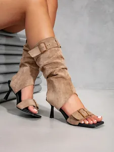 Detail view of brown suede high-heeled sandals with stylish buckle and boot-style upper.