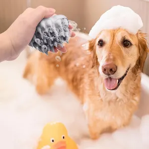 Grey silicone pet bath massage brush being used on a dog in a bathtub with foam.