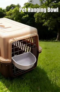 Detail view of a grey hanging pet bowl attached to an airline crate door outdoors