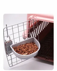 Close-up of gray hanging pet bowl attached to a crate door with dry food inside