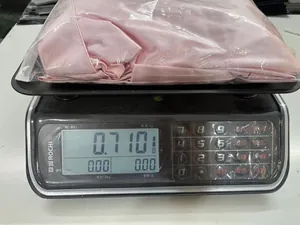 Product weight demonstration of pink satin two-piece set showing 0.710kg on scale