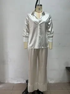 Detailed view of white satin pajama set featuring button-down shirt and long pants.
