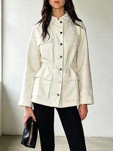 Detail einer weißen Arbeitsjacke mit tailliertem Kordelzug und funktionalen Pattentaschen