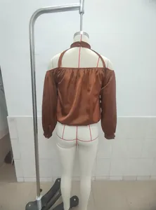 Detailed back view of a brown matte satin off-the-shoulder blouse on a white mannequin
