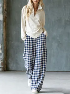 Vue d'un mannequin portant un pantalon large à carreaux rétro et un haut en maille beige.