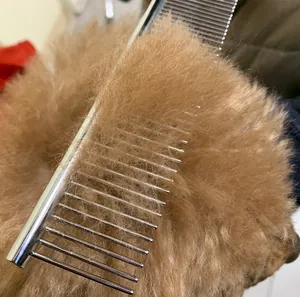 Detailed macro view of professional stainless steel pet grooming comb teeth in fluffy fur
