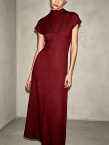 Detail shot of elegant burgundy high-neck maxi dress with minimalist textured fabric