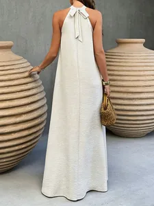 Vue arrière d'une robe longue dos nu beige avec tissu texturé et nœud attaché au cou