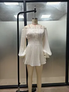 Close-up detail view of a white off-the-shoulder pleated long-sleeved dress on a mannequin