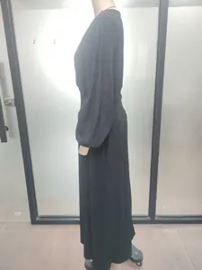 Side view of a black crinkled maxi dress with smocked waist and long sleeves