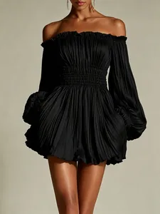 Detail of elegant black off-the-shoulder pleated long sleeve mini dress on model.