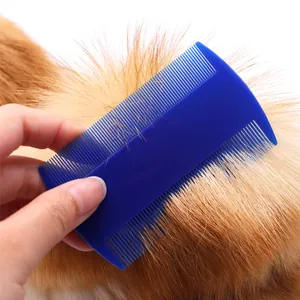 Double-sided blue plastic flea and lice comb for pets being used on thick ginger fur
