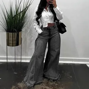 Full view of grey wide-leg flared denim jeans with raw fringe hem and washed finish.