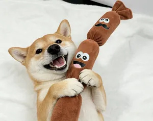 Shiba Inu che abbraccia un gioco di peluche a forma di salsiccia su coperta bianca