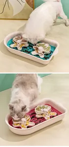 White dog and fluffy cat interacting with a sailboat-themed pet puzzle slow feeder tray