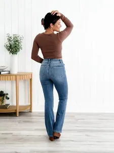 Vue arrière d'un jean bleu évasé à taille haute pour femme dans un décor de maison