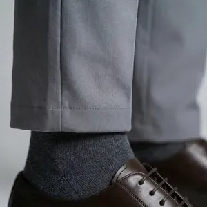 Close-up of grey elastic business pants cuff with brown leather shoes