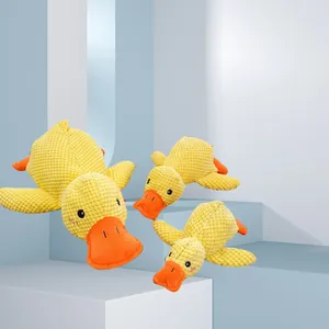 Drie gele pluche piepende eendenspeeltjes voor honden op een modern geometrisch platform
